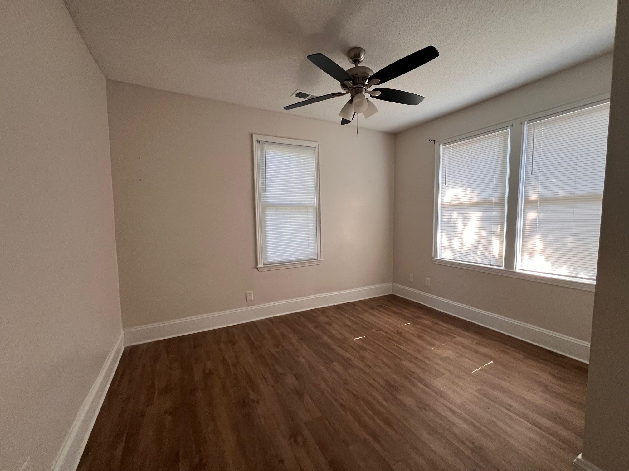 734 Spring Street Memphis, TN 38112 - Photo 12 of 13 an empty room with wooden floor fan and windows