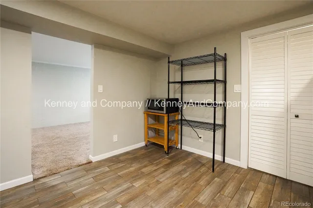 an empty room with wooden floor cabinet and windows