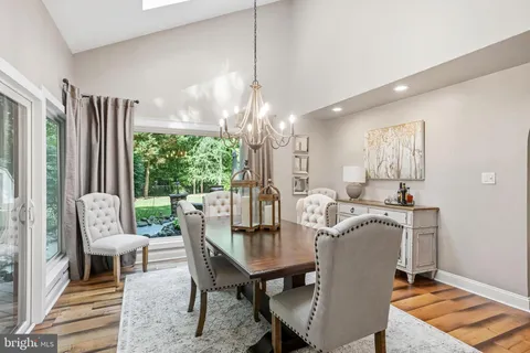 a kitchen with stainless steel appliances kitchen island granite countertop a refrigerator a oven a sink dishwasher and white cabinets with wooden floor