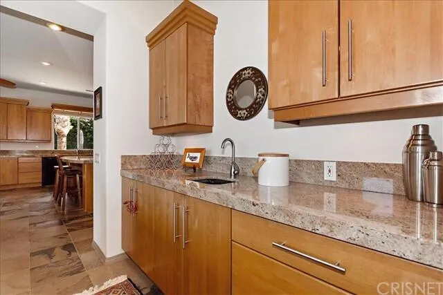 a kitchen with granite countertop a sink a stove top oven and cabinetry