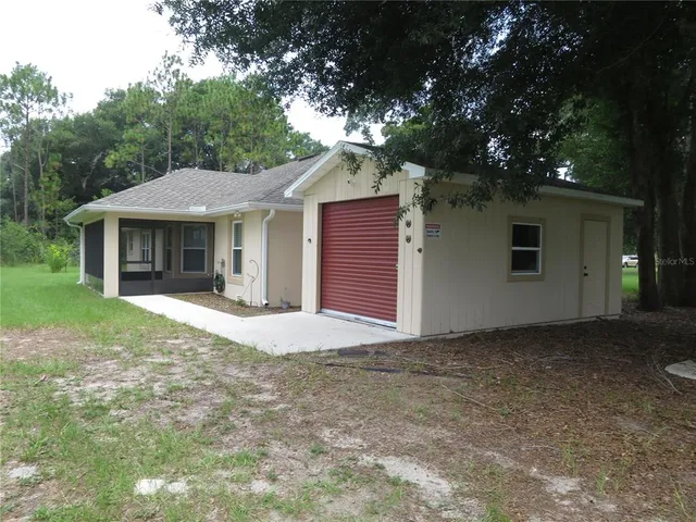 a view of a house with a yard potted plants and a table