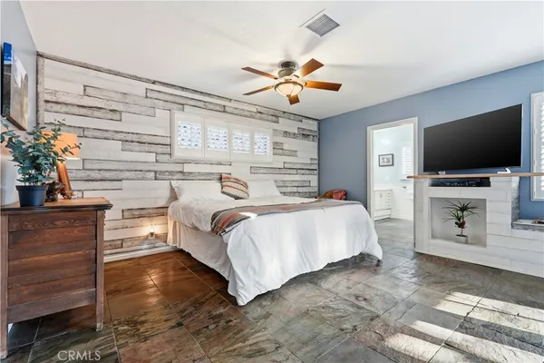 a bedroom with a large bed a flat tv screen and a chandelier