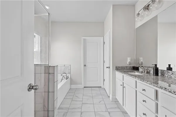 a spacious bathroom with a granite countertop sink a mirror and a shower