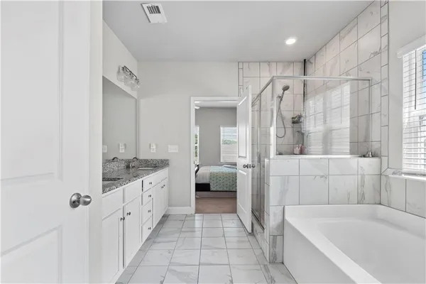a bathroom with a granite countertop sink a mirror a bathtub and shower