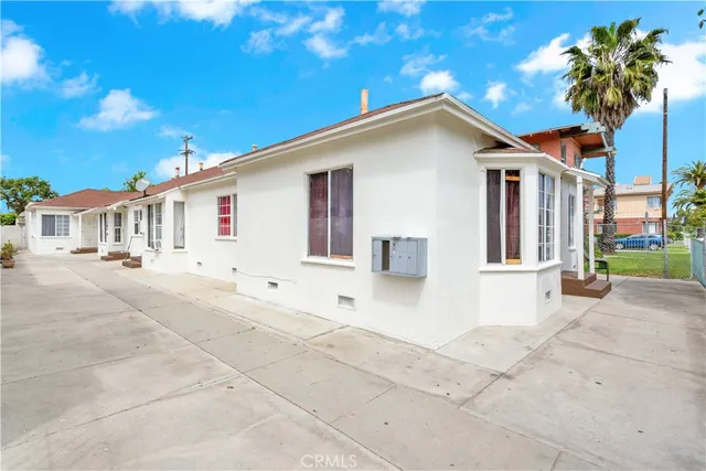 a view of white house with a yard and potted plants