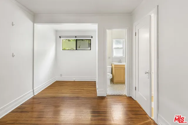 a view of an empty room with wooden floor and a bathroom