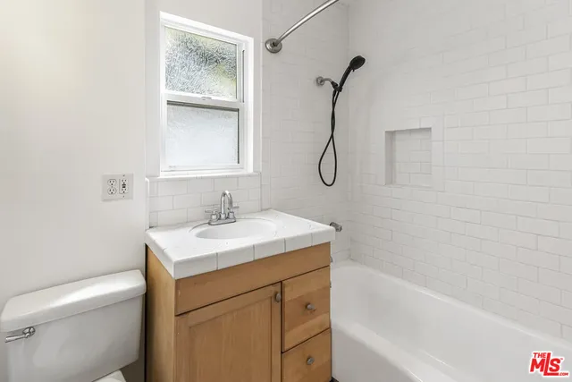 a bathroom with a granite countertop sink a toilet and shower