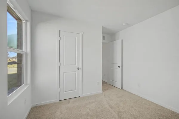 a view of an empty room with windows and closet