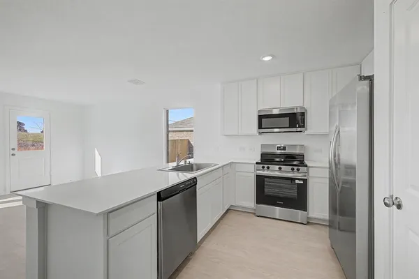 a kitchen with stainless steel appliances granite countertop a stove a sink and a refrigerator