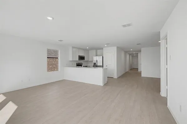 a view of empty room with kitchen and window