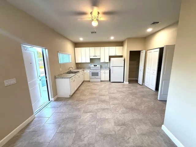 a large white kitchen with stainless steel appliances a refrigerator a stove a microwave oven cabinets and a dining table