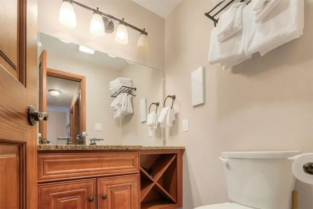 a bathroom with a granite countertop sink a toilet and a mirror