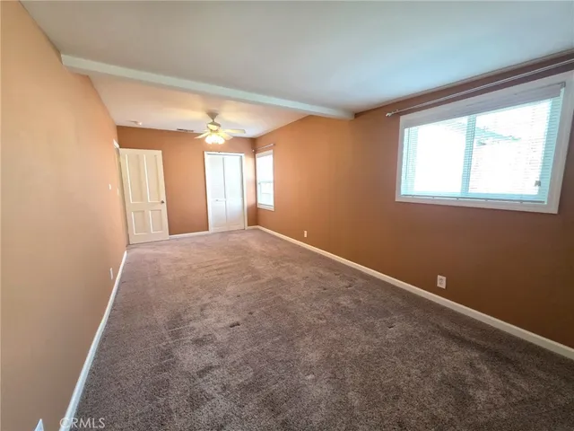a view of a big room with windows and chandelier fan