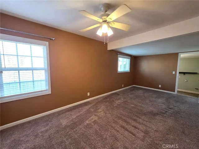 an empty room with windows and chandelier fan