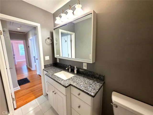 a bathroom with a granite countertop sink a mirror and a toilet