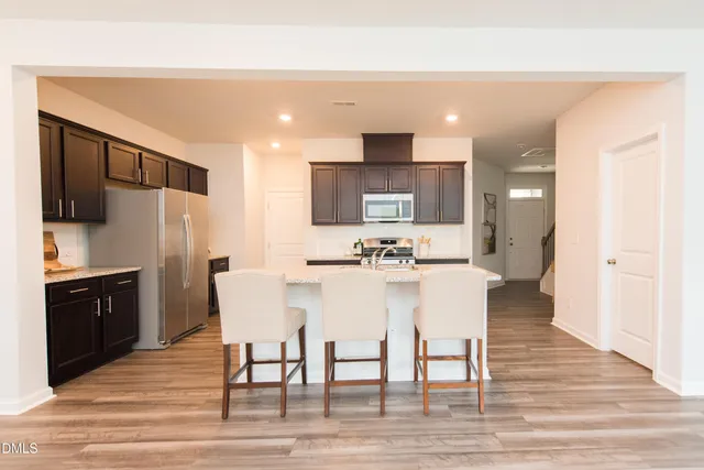 a kitchen with stainless steel appliances kitchen island granite countertop a refrigerator and a stove top oven