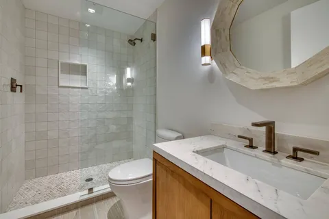 a bathroom with a granite countertop sink toilet a mirror and shower
