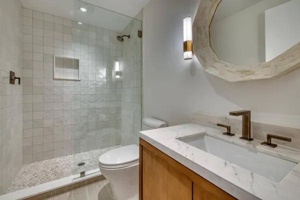 a bathroom with a granite countertop sink toilet a mirror and shower