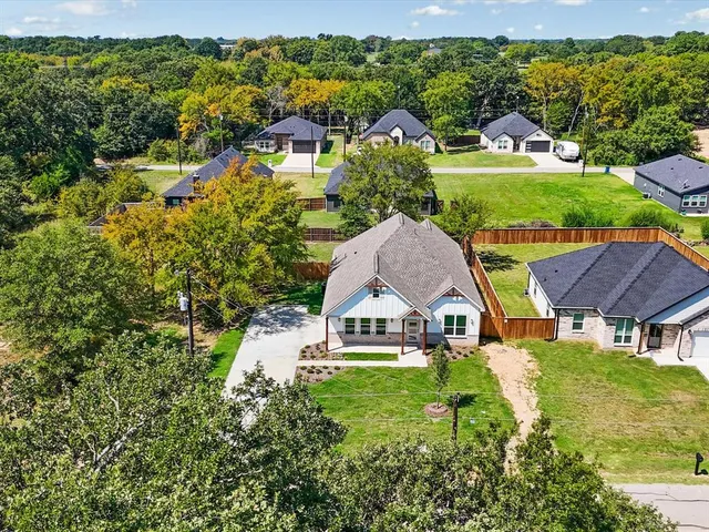 an aerial view of residential houses with outdoor space and trees