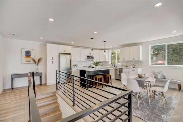 a kitchen with stainless steel appliances kitchen island granite countertop a table chairs sink and cabinets