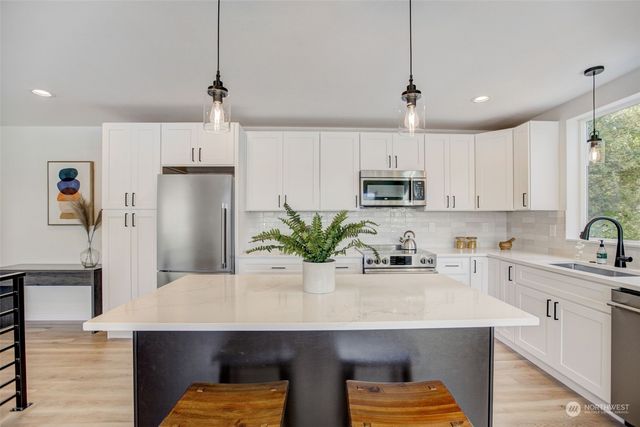a kitchen with kitchen island a sink stainless steel appliances and cabinets