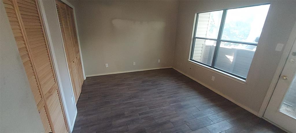 7340 Skillman Street, Unit 512 Dallas, TX 75231 - Photo 8 of 15 an empty room with wooden floor and windows