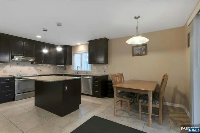 a kitchen with kitchen island granite countertop a sink and a stove