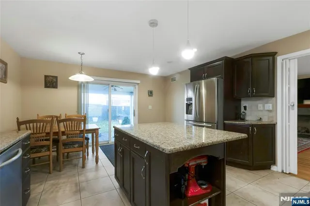 a kitchen with granite countertop kitchen island stainless steel appliances sink cabinets dining table and chairs