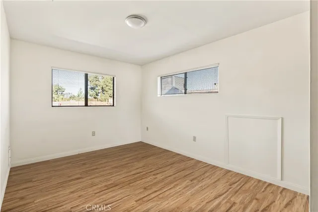 a view of an empty room with wooden floor and closet