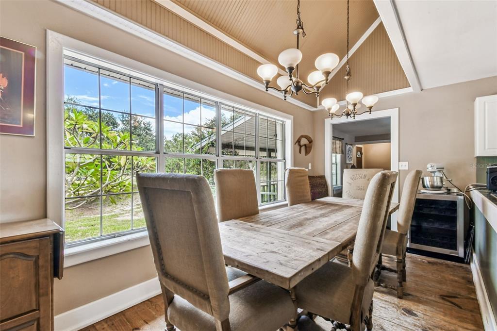 15019 Carlton Lake Road Wimauma, FL 33598 - Photo 15 of 89 a dining room with wooden floor a chandelier a wooden table and chairs