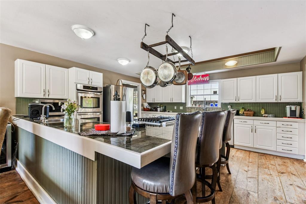 15019 Carlton Lake Road Wimauma, FL 33598 - Photo 16 of 89 a kitchen with stainless steel appliances granite countertop a sink dishwasher a stove and a refrigerator with wooden floor