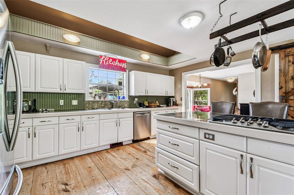 15019 Carlton Lake Road Wimauma, FL 33598 - Photo 17 of 89 a kitchen with stainless steel appliances white cabinets and wooden floors