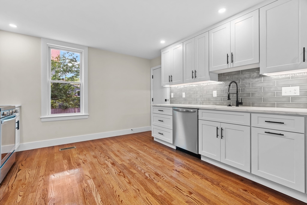 37 George Street, Unit 37 Newton, MA 02458 - Photo 8 of 35 a kitchen with stainless steel appliances granite countertop a stove a sink and white cabinets with wooden floor