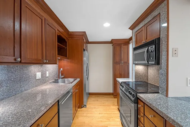a kitchen with stainless steel appliances granite countertop a sink a stove and a refrigerator