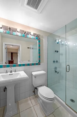 a bathroom with a toilet a sink a mirror and shower