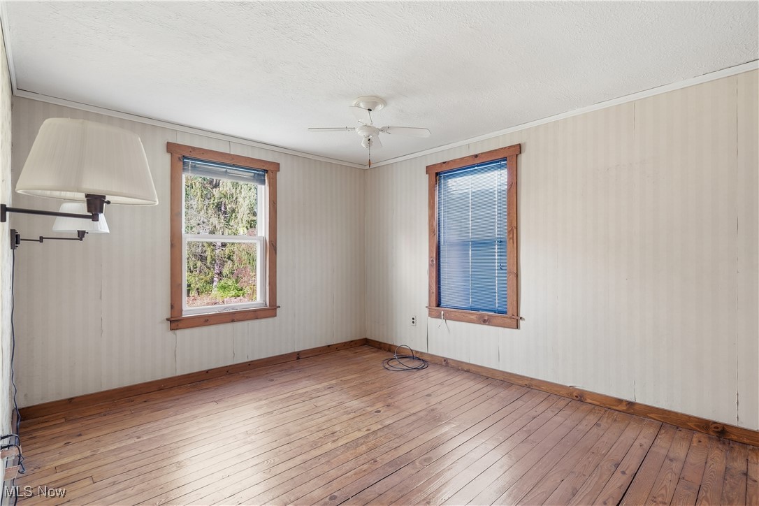 3275 Ranfield Road Kent, OH 44240 - Photo 17 of 33 Unfurnished room with hardwood / wood-style flooring, crown molding, a ceiling fan, and a textured ceiling