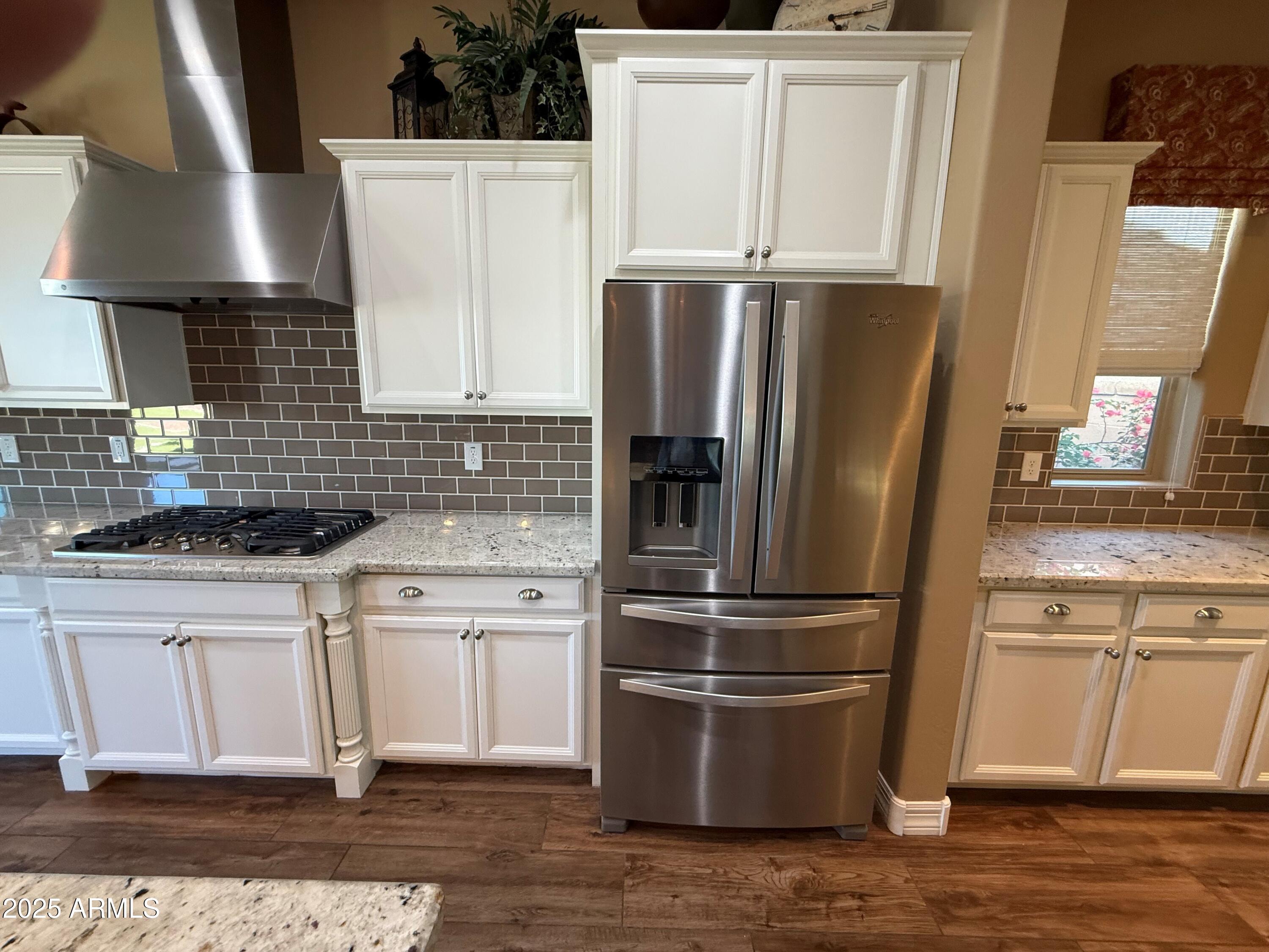 2709 North Black Rock Road Buckeye, AZ 85396 - Photo 19 of 74 a kitchen with stainless steel appliances granite countertop a refrigerator a stove a sink and white cabinets with wooden floor