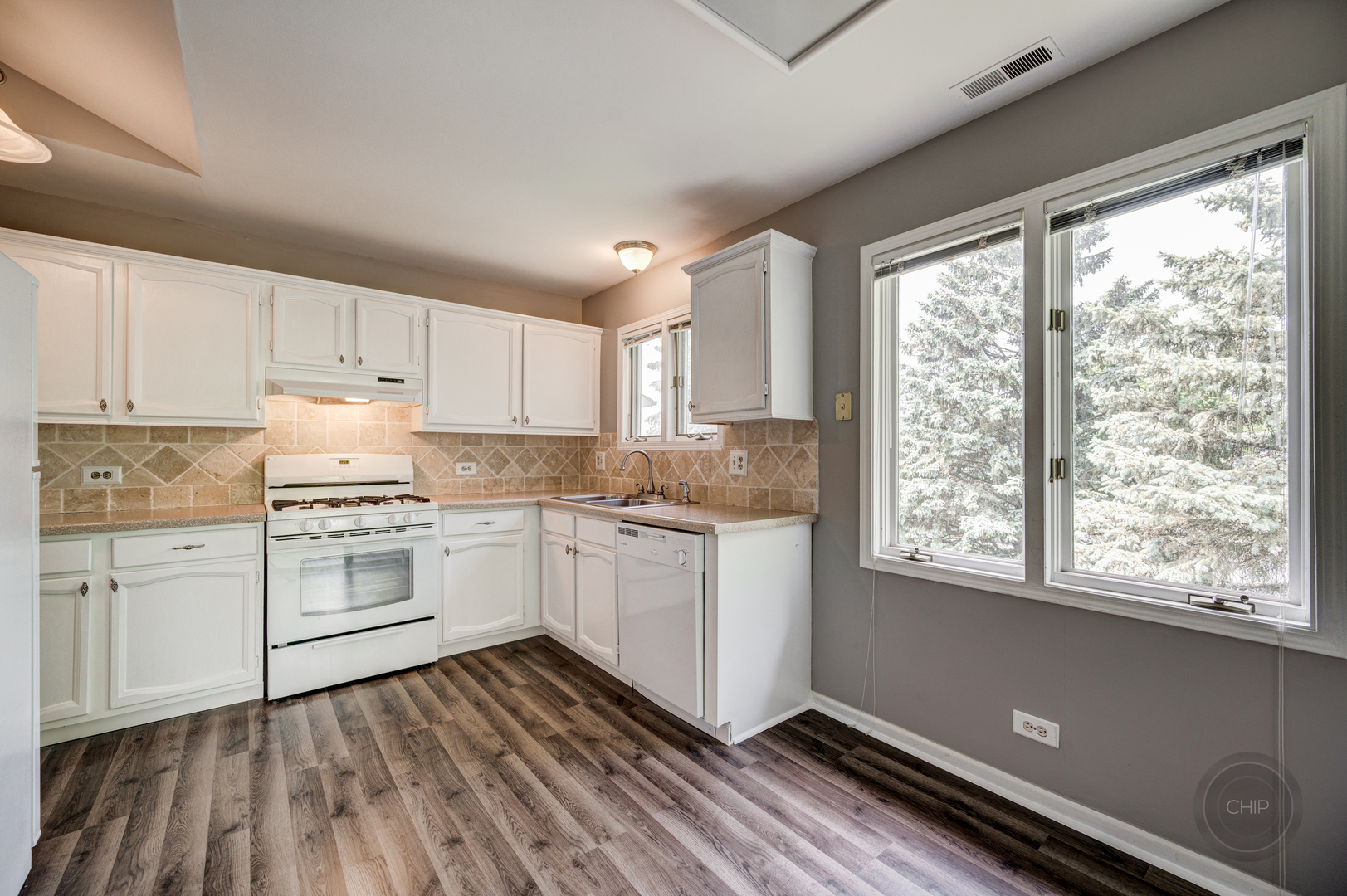 985 West Court, Unit D Naperville, IL 60563 - Photo 12 of 29 a kitchen with granite countertop white cabinets and white appliances with wooden floor