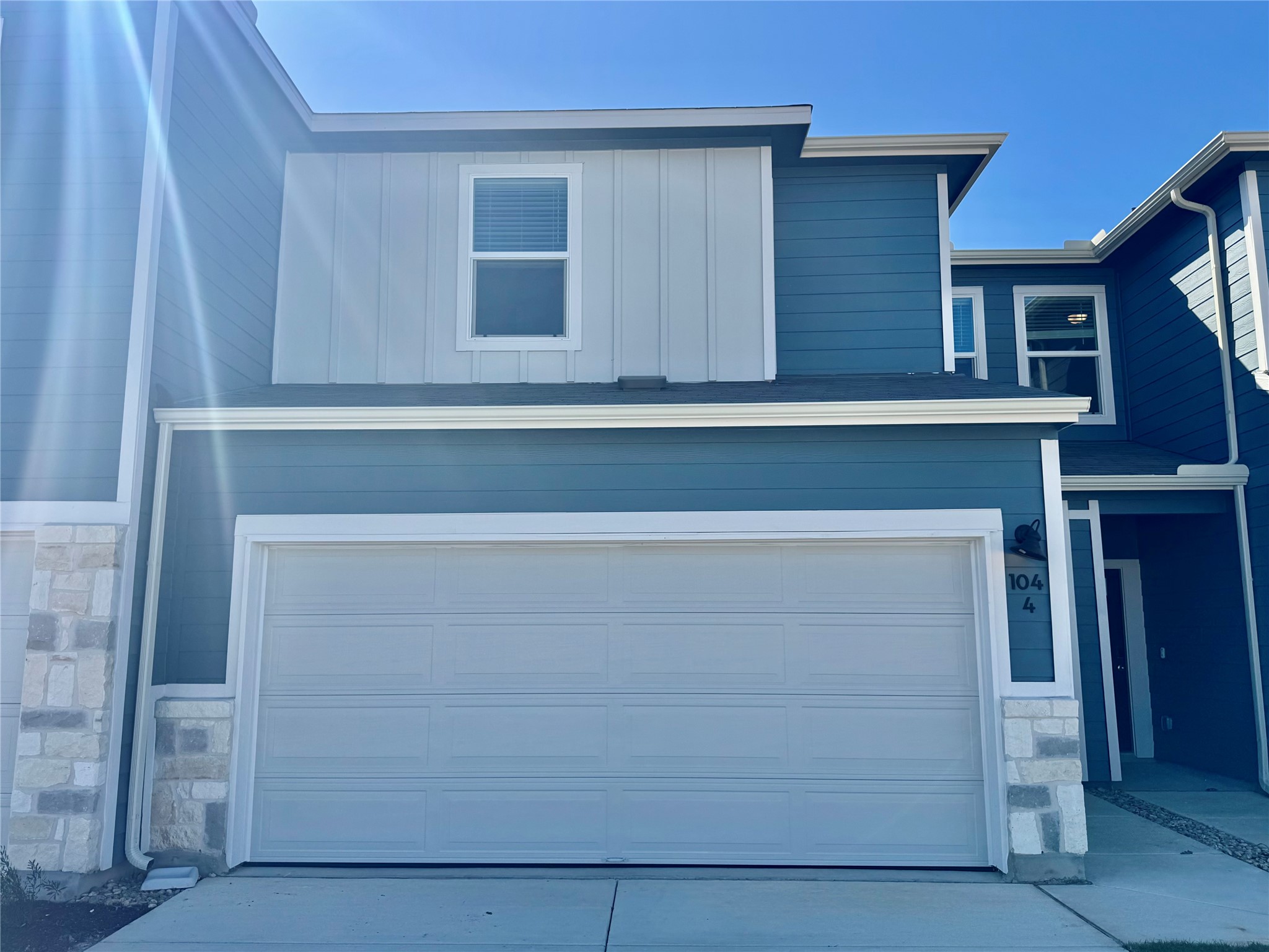 View of front of property featuring stone siding, a garage, board and batten siding, and driveway