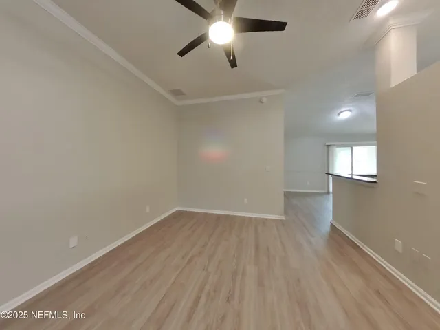an empty room with wooden floor ceiling fan and windows