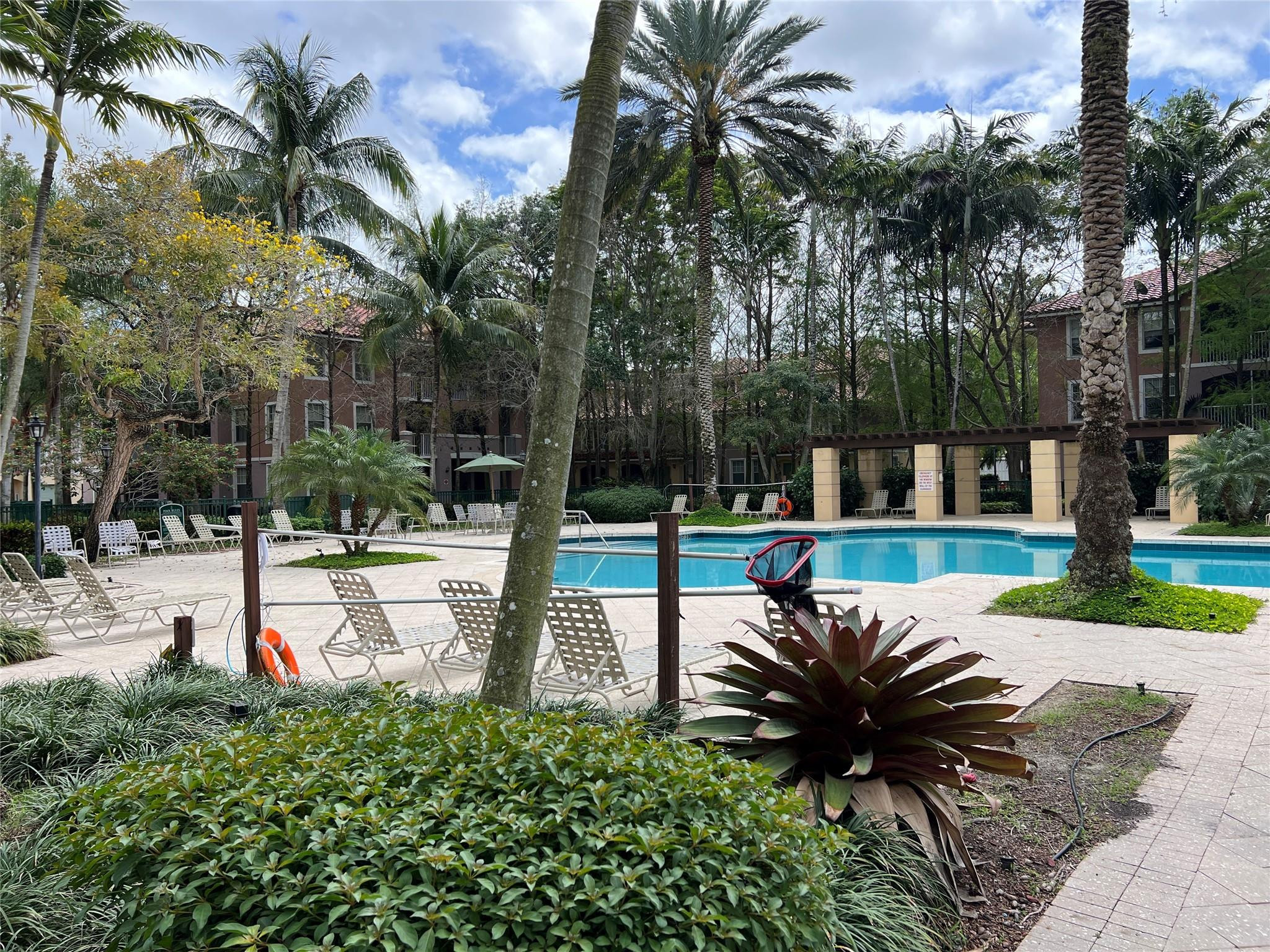 6812 West Sample Road, Unit 6812 Coral Springs, FL 33067 - Photo 2 of 27 a view of a garden with a bench and palm trees