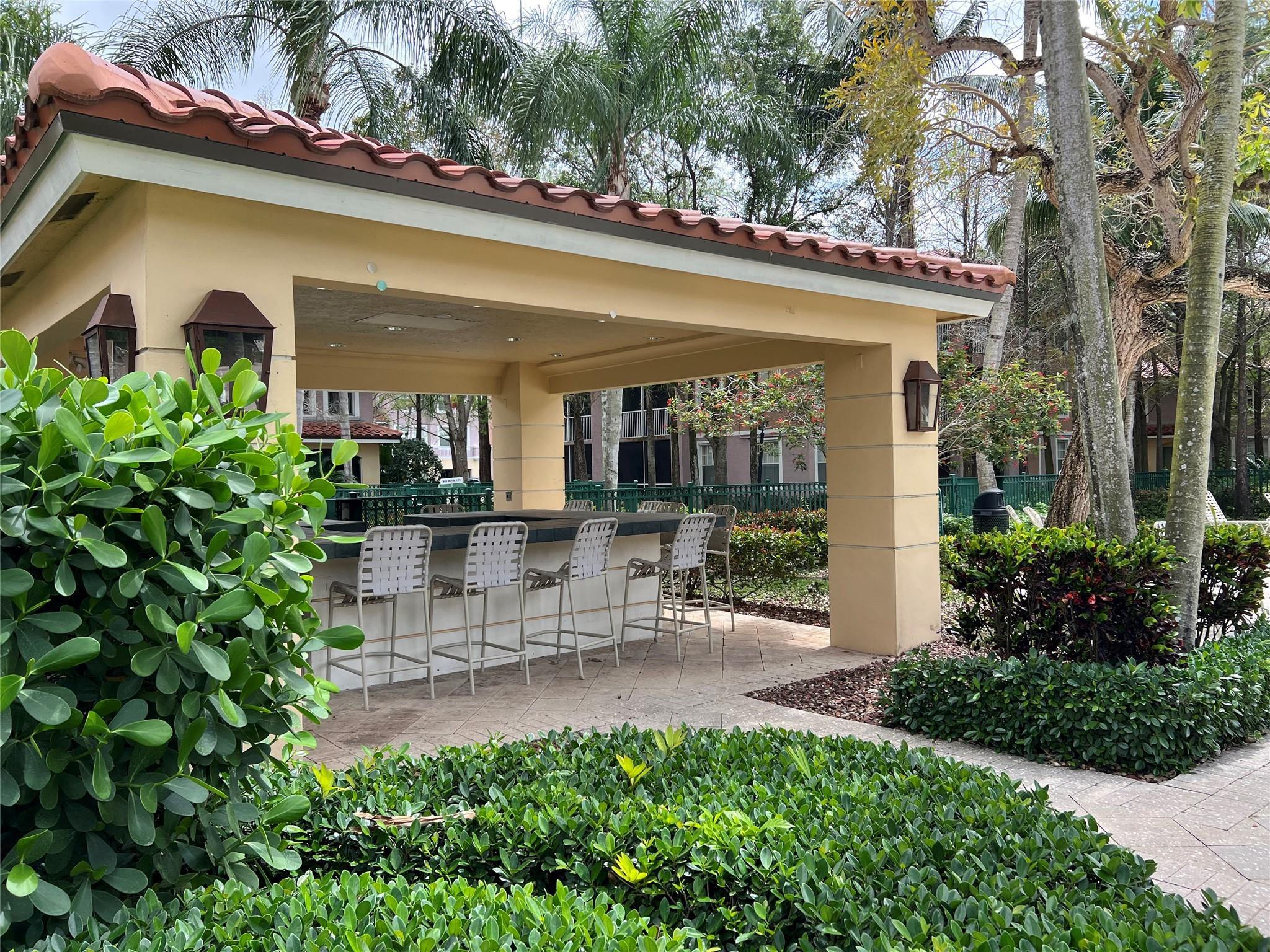 6812 West Sample Road, Unit 6812 Coral Springs, FL 33067 - Photo 23 of 27 a view of a patio with table and chairs potted plants and floor to ceiling window