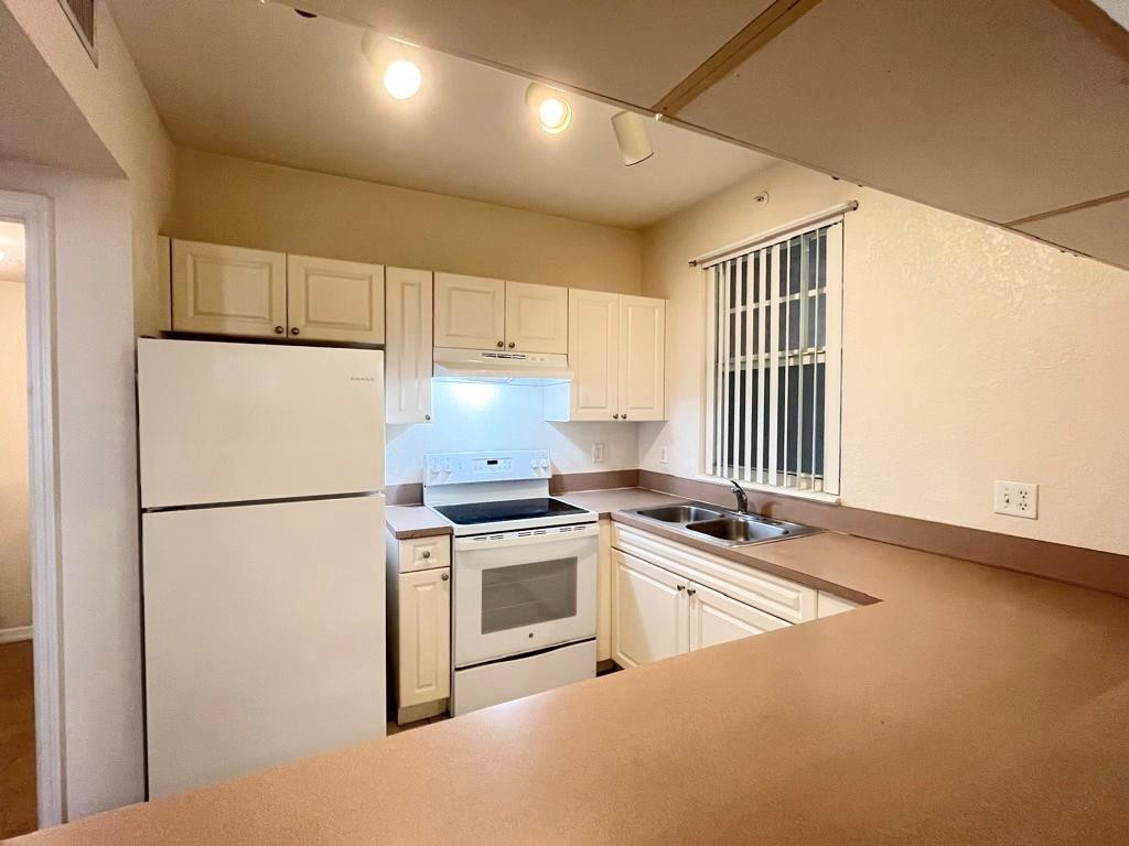 6812 West Sample Road, Unit 6812 Coral Springs, FL 33067 - Photo 8 of 27 a kitchen with granite countertop white cabinets and white appliances