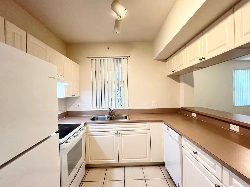 6812 West Sample Road, Unit 6812 Coral Springs, FL 33067 - Photo 9 of 27 a kitchen with a sink stove top oven and cabinets