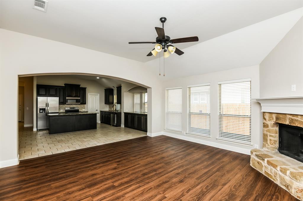 826 Graham Drive Burleson, TX 76028 - Photo 4 of 18 a view of a living room kitchen with a flat screen tv wooden floor and a fireplace