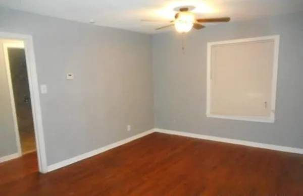 an empty room with a window and a fan