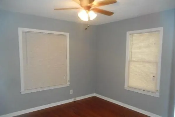 an empty room with a window and a chandelier fan