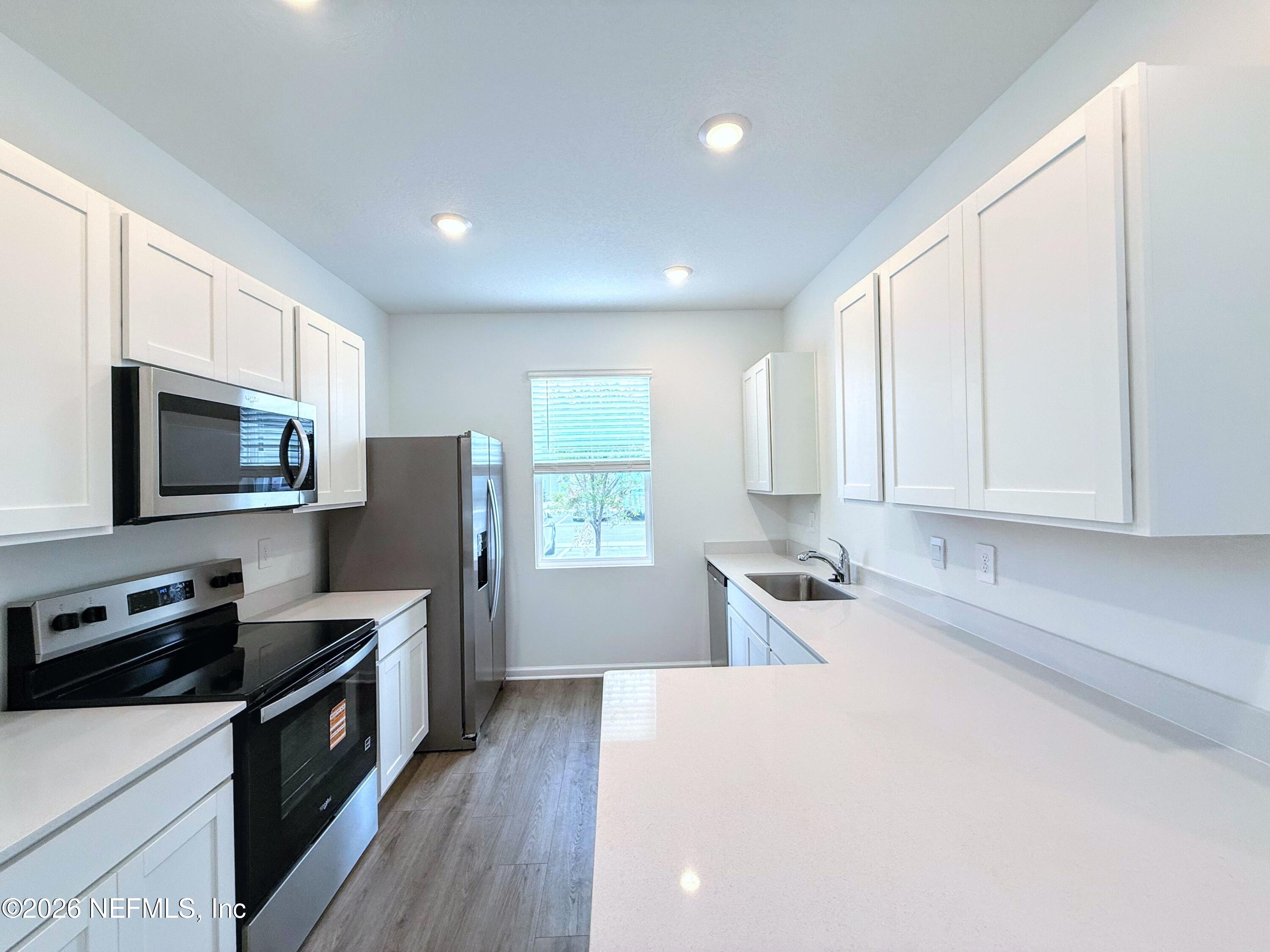 131 Palmetto Rdg Road St. Augustine, FL 32095 - Photo 4 of 20 a kitchen with stainless steel appliances a stove top oven a sink a refrigerator white cabinets and wooden floor