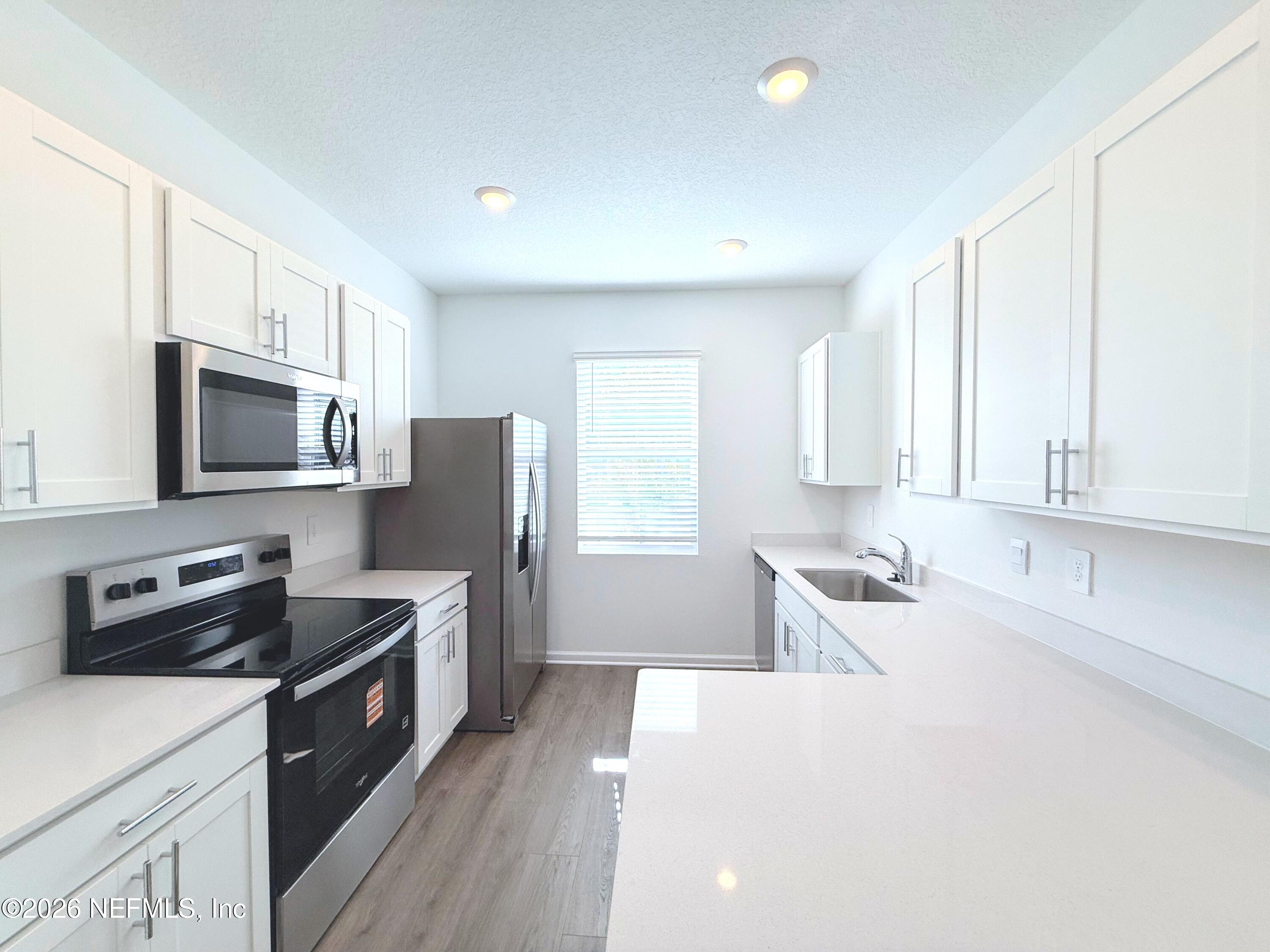 131 Palmetto Rdg Road St. Augustine, FL 32095 - Photo 5 of 22 a kitchen with stainless steel appliances a stove top oven a sink a refrigerator white cabinets and wooden floor