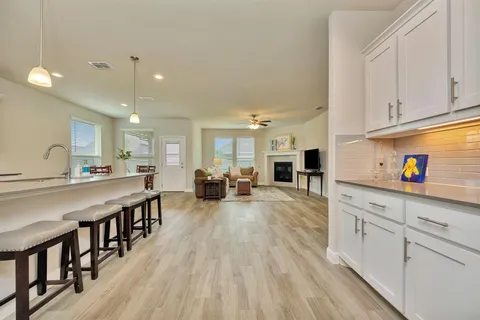 a large white kitchen with lots of counter space a sink appliances and a center island